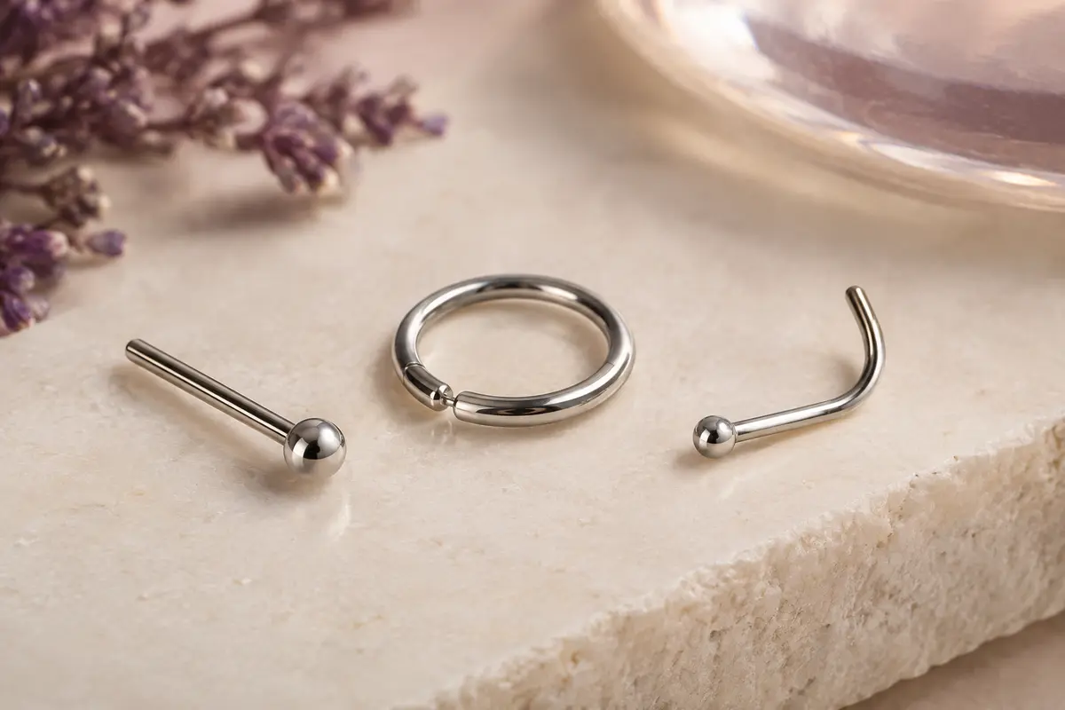 Piercing de nez en acier inoxydable et anneau posés côte à côte pour comparer leurs formes.