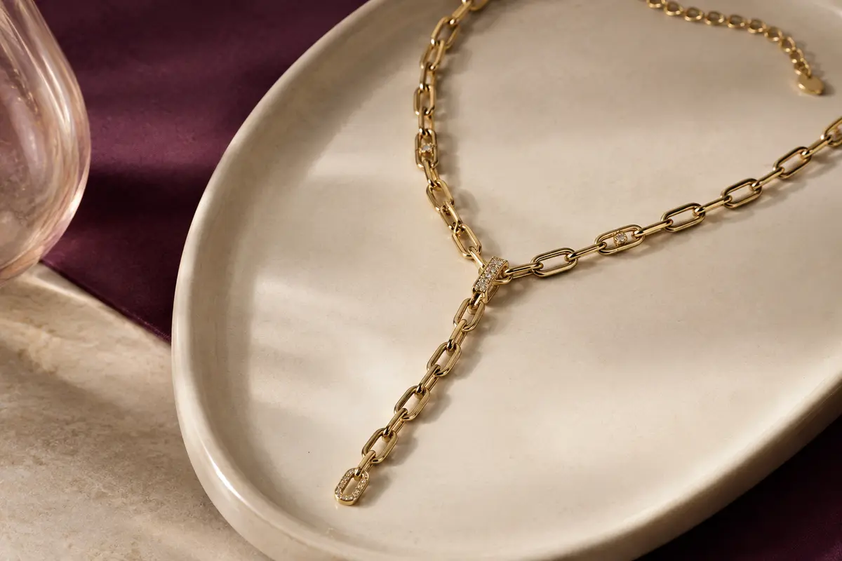 Collier Y doré à maille marine et chaîne ajustable posé sur un plateau en céramique claire