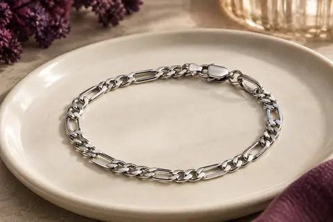 Bracelet argenté Flintronic à maille Figaro facettée, posé sur une céramique claire.