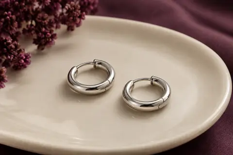Paire de créoles lisses en acier argenté de 18 mm posées sur un plateau en céramique ivoire