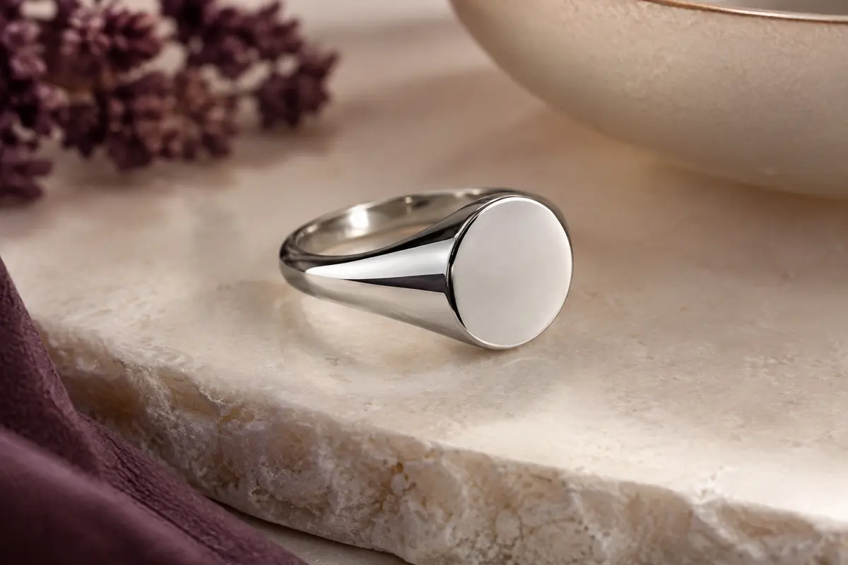 Chevalière argentée en acier inoxydable à face ronde de 12 mm, présentée seule sur une pierre claire.