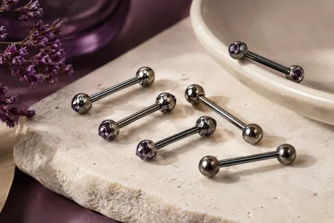 Lot de barbells droits noirs à cristaux disposés sur une surface en pierre claire