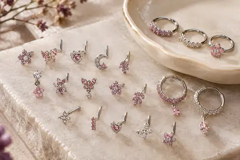 Assortiment de clous et d’anneaux de nez aux motifs variés, posé sur une pierre claire