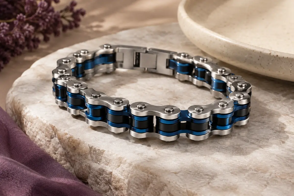 Bracelet chaîne en acier inoxydable aux maillons noirs et bleus, posé sur une pierre claire