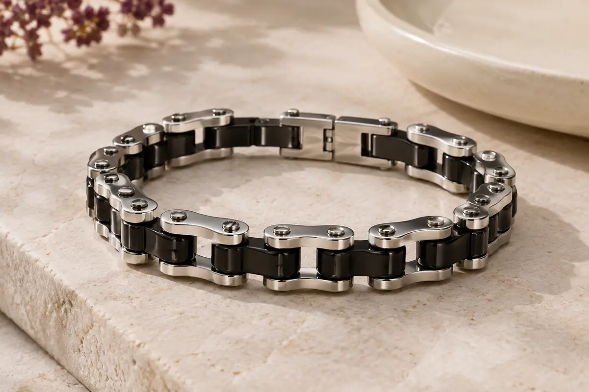 Bracelet chaîne pour homme aux maillons inspirés de la moto, en tons noirs et argentés, posé sur une pierre claire.