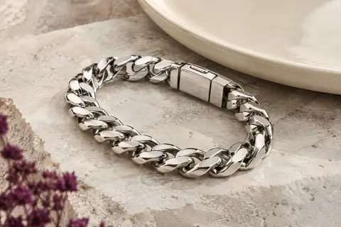 Bracelet gourmette argenté à maille polie de 12 mm posé sur une pierre claire